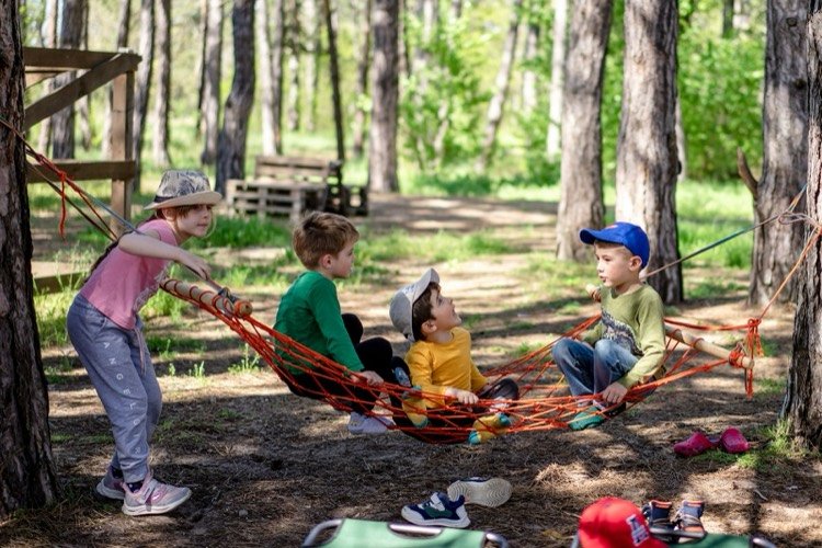 Niños jugando juntos en una hamaca entre árboles